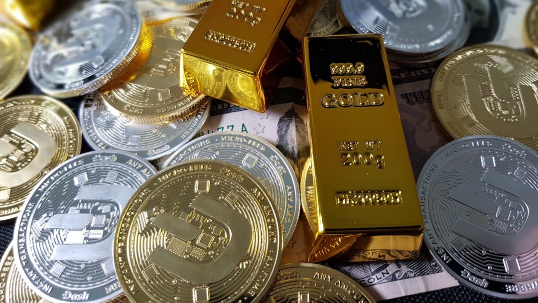 Gold bars and cryptocurrency coins stacked together with paper currency visible in the background.